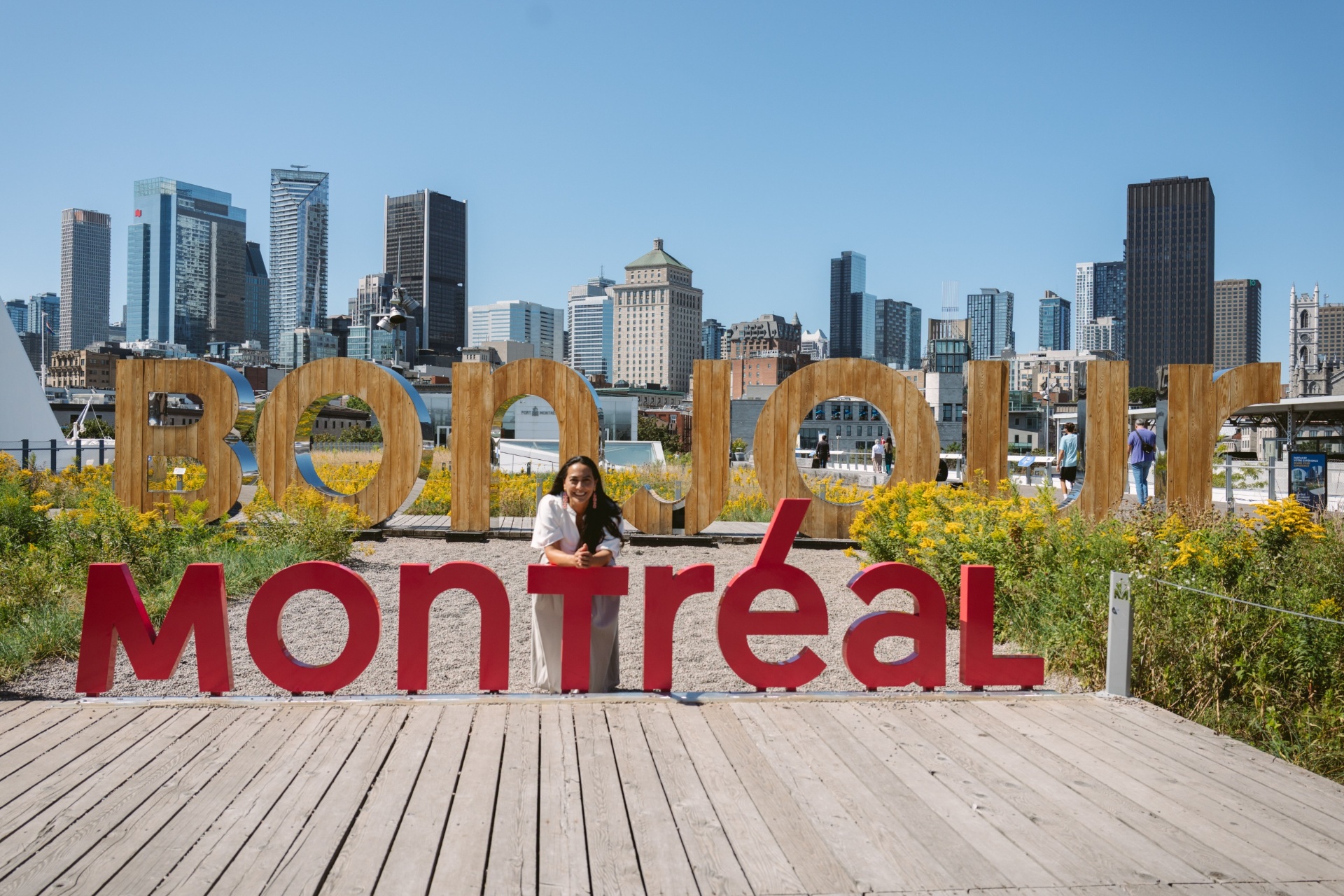 Cristina Uribe detrás del letrero Bonjour Montréal frente al skyline de la ciudad